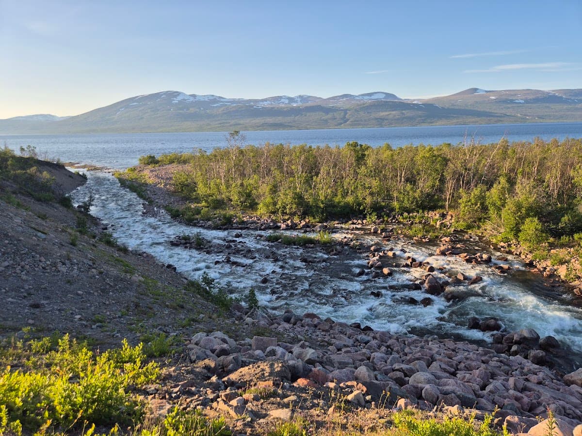 Rastplats Bessesjohka vid E10 med ett slingrande vattendrag i ett nordiskt fjällandskap.
