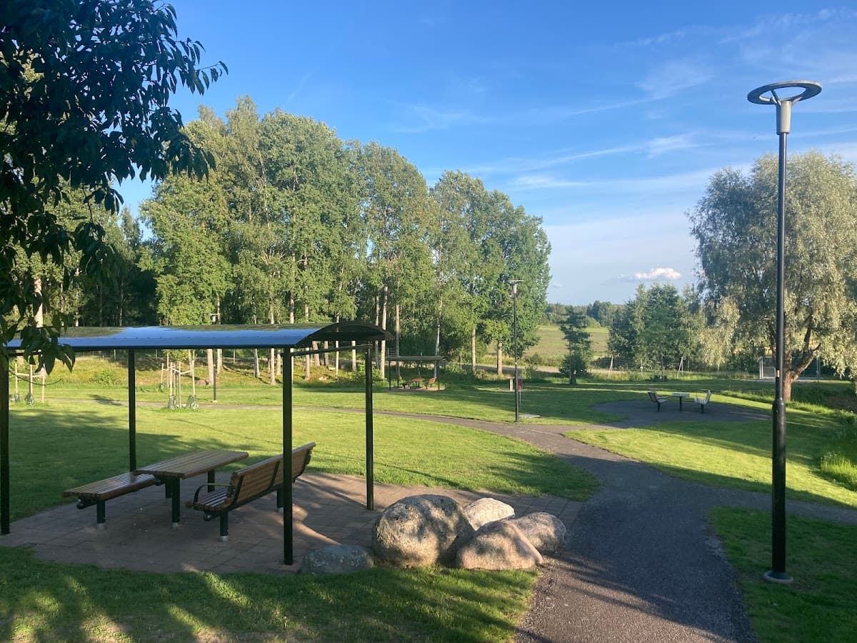 Rastplats Högsjön vid E20 med utsikt över sjön, omgiven av skog och sittplatser.