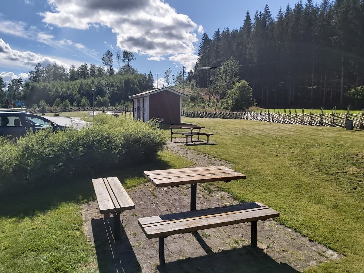 Vy över rastplats Övrarp längs riksväg 27 i Småland med sittplatser och omgivande skog.