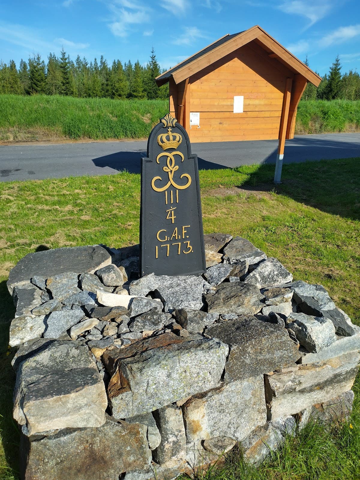 Rastplats Rödviken vid Riksväg 27 med lummig skog och utsikt över en stilla vik.