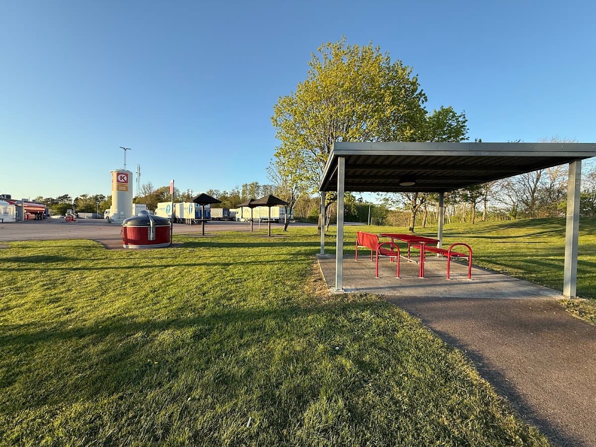 Rastplats Snapparp V längs E6 i Halland med grönskande träd och sittplatser.