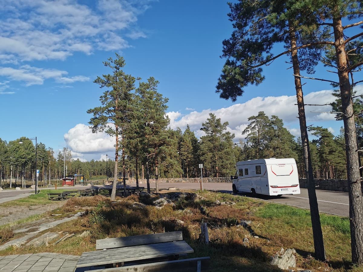 Vy över rastplats Sörmon vid E18 nära Karlstad med sittplatser och omgivande skog.